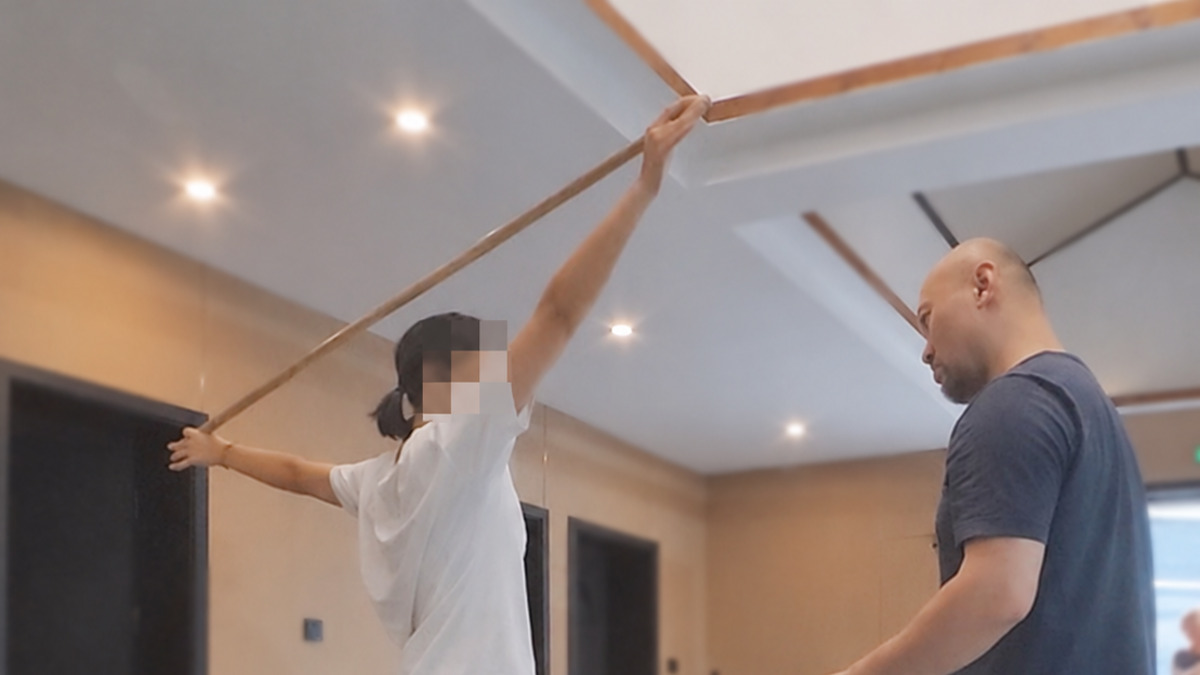 Frank观察参与者持杆抬臂的动作，参与者面部保留客户提供的打码
